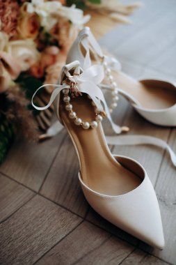 Gelinin kıyafetinin detaylarının yakın plan çekimi modern bir düğün aksesuarı, yüksek topuklu ayakkabılar, modern bir gelin buketi. Düğün hazırlıkları.