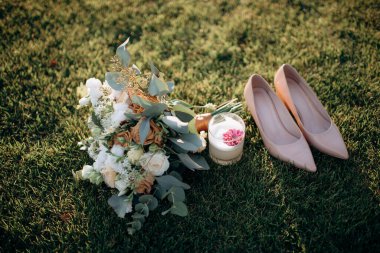 Gelinin kıyafetinin detaylarının yakın plan çekimi modern bir düğün aksesuarı, yüksek topuklu ayakkabılar, modern bir gelin buketi. Düğün hazırlıkları.