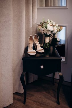 Çekici bir gelin için zarif düğün aksesuarlarının modern bir kompozisyonu. Alyanslar, düğün buketleri, parfüm şişesi, mücevherler. Gelinin Hazırlanması