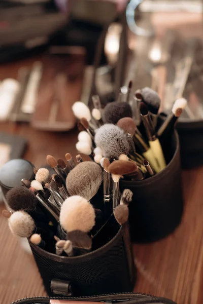 Make-up artist\'s tools, brushes, applicators, cosmetics are laid out on the table during work