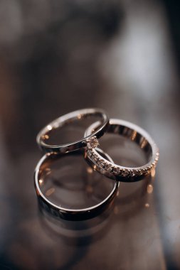 Nişan yüzükleriyle birlikte yakın plan bir ayna yüzeyinde yatıyor.