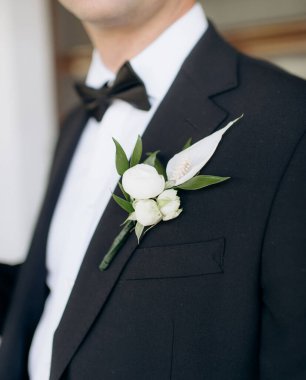 Damadın ceketinin yakasında solmuş yapraklar olan beyaz çiçekli yaka çiçeği.