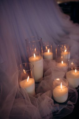 Mavi akşam ışığında yapılan bir düğün töreninde büyük, beyaz, volkanik mumlar yerde duruyor. Sıcak mum ışığı. Sıcak ışık, soğuk gölgeler. Parlak cam. Mumlar yerdeki zarif cam vazolarda yakılır. Düğün için süslemeler.