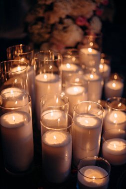 Mavi akşam ışığında yapılan bir düğün töreninde büyük, beyaz, volkanik mumlar yerde duruyor. Sıcak mum ışığı. Sıcak ışık, soğuk gölgeler. Parlak cam. Mumlar yerdeki zarif cam vazolarda yakılır. Düğün için süslemeler.