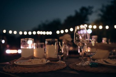 Mavi akşam ışığında yapılan bir düğün töreninde büyük, beyaz, volkanik mumlar yerde duruyor. Sıcak mum ışığı. Sıcak ışık, soğuk gölgeler. Parlak cam. Mumlar yerdeki zarif cam vazolarda yakılır. Düğün için süslemeler.