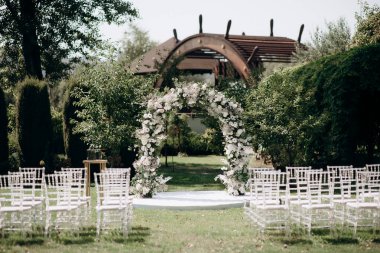 Yeşil çimenlikteki bir düğün töreninin süslemeleri. Görkemli büyük ve şık kemer ve chiavari sandalyeler