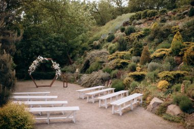 Beyaz çiçeklerin doğal minimalist düğün dekoru ve ahşap sandalyeli yeşil çimlerin üzerindeki yeşillik.