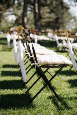Ahşap sandalyeli düğün koridoru, yeşil bir çayırda doğal, kırsal bir düğün dekoru. Kemer ve ahşap sandalyeli düğün töreni, deniz manzaralı.