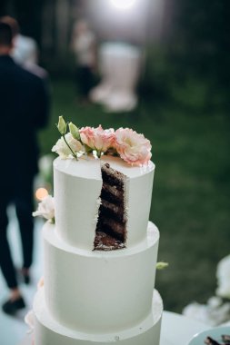 Taze çiçek süslemeli üç katlı beyaz düğün pastası.