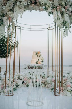 Şeftalili ve beyaz çiçekli üç katlı düğün pastası.