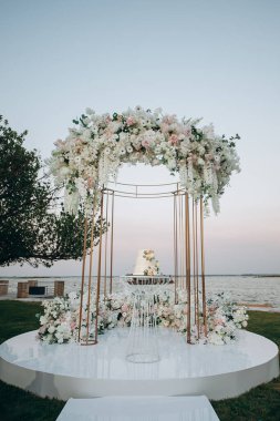 Şeftalili ve beyaz çiçekli üç katlı düğün pastası.