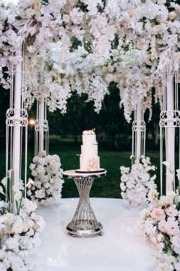 Pembe ve beyaz çiçekli üç katlı beyaz düğün pastası