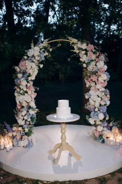 Çiçek kemerli iki katlı beyaz düğün pastası