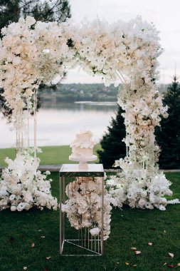 Çiçek kemerli iki katlı beyaz düğün pastası