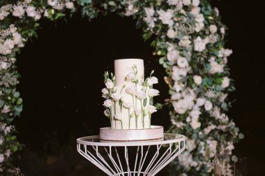 Beyaz çiçekli iki katlı düğün pastası.