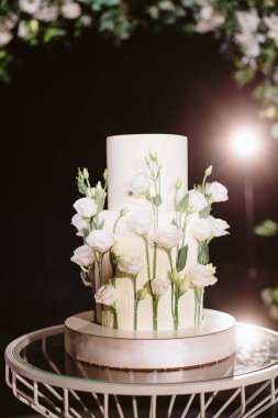 Beyaz çiçekli iki katlı düğün pastası.