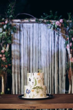 İki katlı beyaz düğün pastası ve ütülenmiş çiçekler.