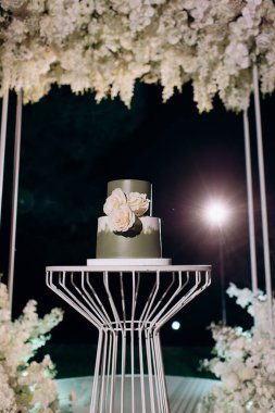 İki katlı koyu yeşil düğün pastası ve beyaz güller.