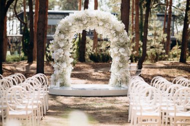 Beyaz narin sandalyeleri ve yumuşak çigila kemeri olan bir çam ormanında güzel bir düğün sahnesi. Doğal ortam huzurlu ve romantik bir atmosfer yaratır.