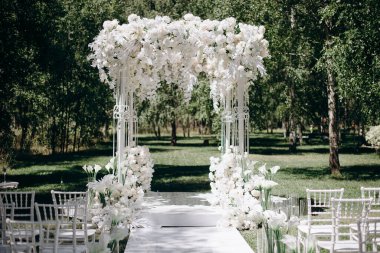 Beyaz narin sandalyeler, el değmemiş beyaz bir koridor ve bol miktarda beyaz çiçeklerle süslenmiş bir kemer içeren bir huş ağacının koruluğunda yapılan büyüleyici bir düğün töreni.