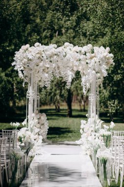 Beyaz narin sandalyeler, el değmemiş beyaz bir koridor ve bol miktarda beyaz çiçeklerle süslenmiş bir kemer içeren bir huş ağacının koruluğunda yapılan büyüleyici bir düğün töreni.