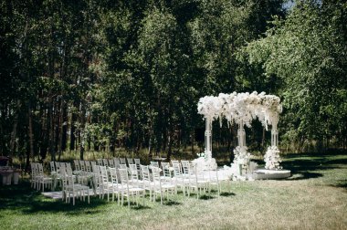Beyaz narin sandalyeler, el değmemiş beyaz bir koridor ve bol bol beyaz çiçeklerle süslenmiş uzun bir kemer içeren bir huş ağacının koruluğunda yapılan büyüleyici bir düğün töreni.
