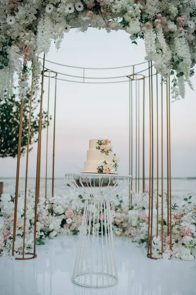 Şeftalili ve beyaz çiçekli üç katlı düğün pastası.