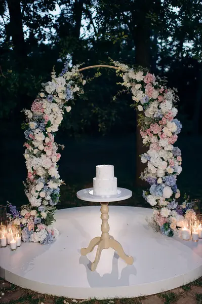 Çiçek kemerli iki katlı beyaz düğün pastası
