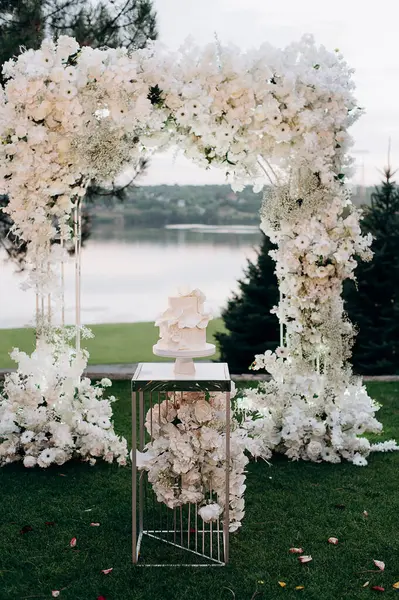 Çiçek kemerli iki katlı beyaz düğün pastası