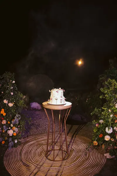 İki katlı beyaz düğün pastası ve ütülenmiş çiçekler.