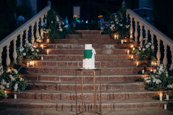 Altın aksanlı üç katlı beyaz ve yeşil düğün pastası.