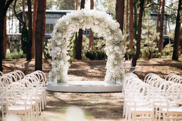 Beyaz narin sandalyeleri ve yumuşak çigila kemeri olan bir çam ormanında güzel bir düğün sahnesi. Doğal ortam huzurlu ve romantik bir atmosfer yaratır.