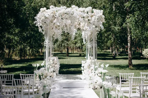 Beyaz narin sandalyeler, el değmemiş beyaz bir koridor ve bol miktarda beyaz çiçeklerle süslenmiş bir kemer içeren bir huş ağacının koruluğunda yapılan büyüleyici bir düğün töreni.