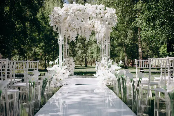 Beyaz narin sandalyeler, el değmemiş beyaz bir koridor ve bol miktarda beyaz çiçeklerle süslenmiş bir kemer içeren bir huş ağacının koruluğunda yapılan büyüleyici bir düğün töreni.