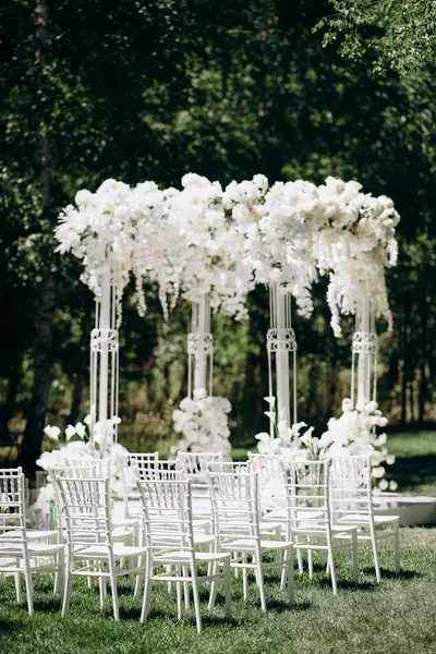 Beyaz narin sandalyeler, el değmemiş beyaz bir koridor ve bol bol beyaz çiçeklerle süslenmiş uzun bir kemer içeren bir huş ağacının koruluğunda yapılan büyüleyici bir düğün töreni.