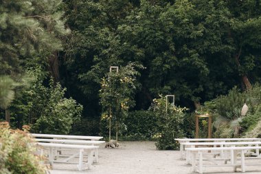 Açık hava seremonisi. Altın çerçeveli, beyaz banklarda dekoratif meyve ağaçları ve yemyeşil çimlerin ortasında çakıllı patikalar, zarif bir düğün ortamı yaratıyor.