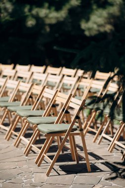 Yeşil yastıklı ahşap katlanır sandalyeler açık havada bir terasta durur.