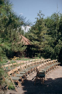 Yeşil yastıklı ahşap katlanır sandalyeler açık havada bir terasta durur.