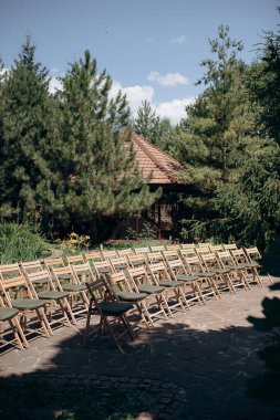 Yeşil yastıklı ahşap katlanır sandalyeler açık havada bir terasta durur.