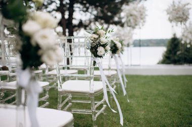 Beyaz çiçek aranjmanlı temiz sandalyeler açık hava etkinliklerinde yeşil bir çimenlik oluşturur.
