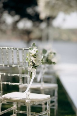 Beyaz çiçek aranjmanlı temiz sandalyeler açık hava etkinliklerinde yeşil bir çimenlik oluşturur.