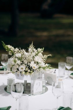 Modern bir vazoda beyaz bir masa örtüsü üzerinde beyaz bir çiçekli süs.