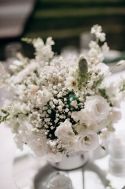 Modern bir vazoda beyaz bir masa örtüsü üzerinde beyaz bir çiçekli süs.