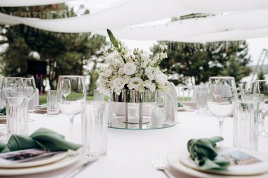 Modern bir vazoda beyaz bir masa örtüsü üzerinde beyaz bir çiçekli süs.