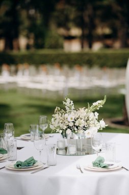 Modern bir vazoda beyaz bir masa örtüsü üzerinde beyaz bir çiçekli süs.