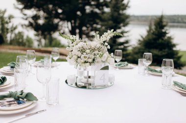 Modern bir vazoda beyaz bir masa örtüsü üzerinde beyaz bir çiçekli süs.