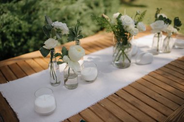 Nazik yapraklarını ve yumuşak dokusunu gösteren beyaz bir okaliptüs çelenginin yakın plan çekimi. Çelenk desenli bir yüzeye yerleştirilmiş, basit ve zarif bir estetik oluşturuyor. Yumuşak ışıklandırma okaliptüsün doğal güzelliğini vurgular.