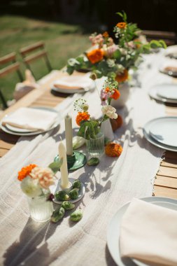 Çiçek aranjmanları ve mumlarla birlikte açık masa. Sıcak, yaz atmosferi