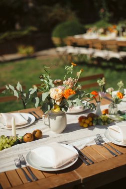 Çiçek aranjmanları ve mumlarla birlikte açık masa. Sıcak, yaz atmosferi