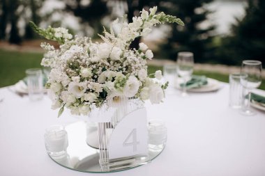 Beyaz çiçekli zarif bir masa ve dört numara. Parlak, açık hava atmosferi